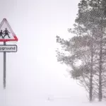 School sign engulfed in snow