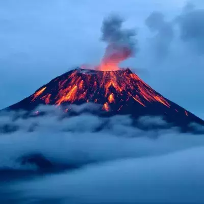 Erupting volcano over sea of clouds
